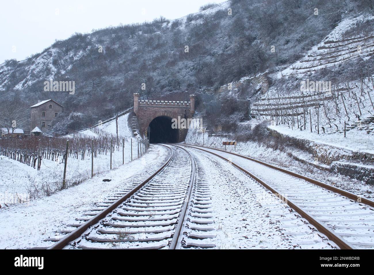 Bad Kreuznach, Germany - February 8, 2021: Rail tracks leading to tunnel through Rotenfels on a cold, grey, snowy winter day in Germany. Stock Photo