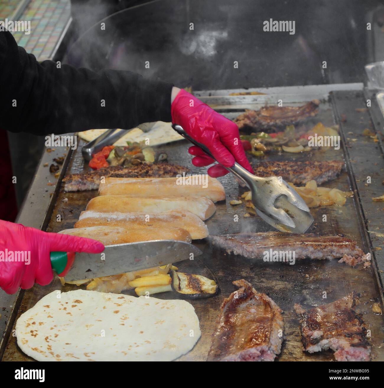 Cook during the preparation of the takeaway food cooked on a hot plate during the village festival Stock Photo