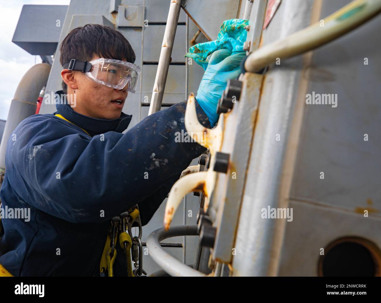 230125-N-QF023-1013  PHILLIPINE SEA (Jan. 25, 2023) Seaman Jiarui Liu, from Queens, New York, wipes down the kingspost during maintenance aboard Arleigh Burke-class guided-missile destroyer USS Benfold (DDG 65). Benfold is assigned to Commander, Task Force (CTF) 71/Destroyer Squadron (DESRON) 15, the Navy’s largest forward-deployed DESRON and the U.S. 7th Fleet’s principal surface force. Stock Photo