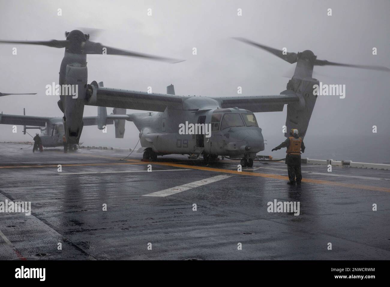 230124-N-IV962-1006    Aviation Boatswain’s Mate (Handling) 3rd Class Ernest Pelicano directs an MV-22 Osprey, assigned to Marine Medium Tiltrotor Squadron (VMM) 362 (Rein.), 13th Marine Expeditionary Unit (MEU), on the flight deck of amphibious assault ship USS Makin Island (LHD 8), Jan. 2, 2023 in the South China Sea. The Makin Island ARG/13th MEU serves as America’s forward-postured force, ready to respond to emergencies and threats with flexible, adaptable force packages that are capable of a wide array of missions. The Makin Island Amphibious Ready Group, comprised of amphibious assault s Stock Photo