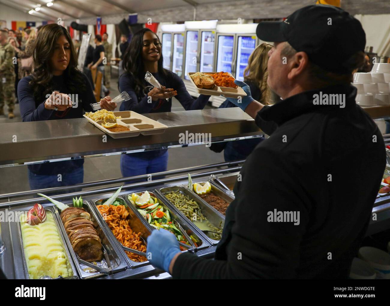 A dining facility worker serves a Houston Texans cheerleader lunch at