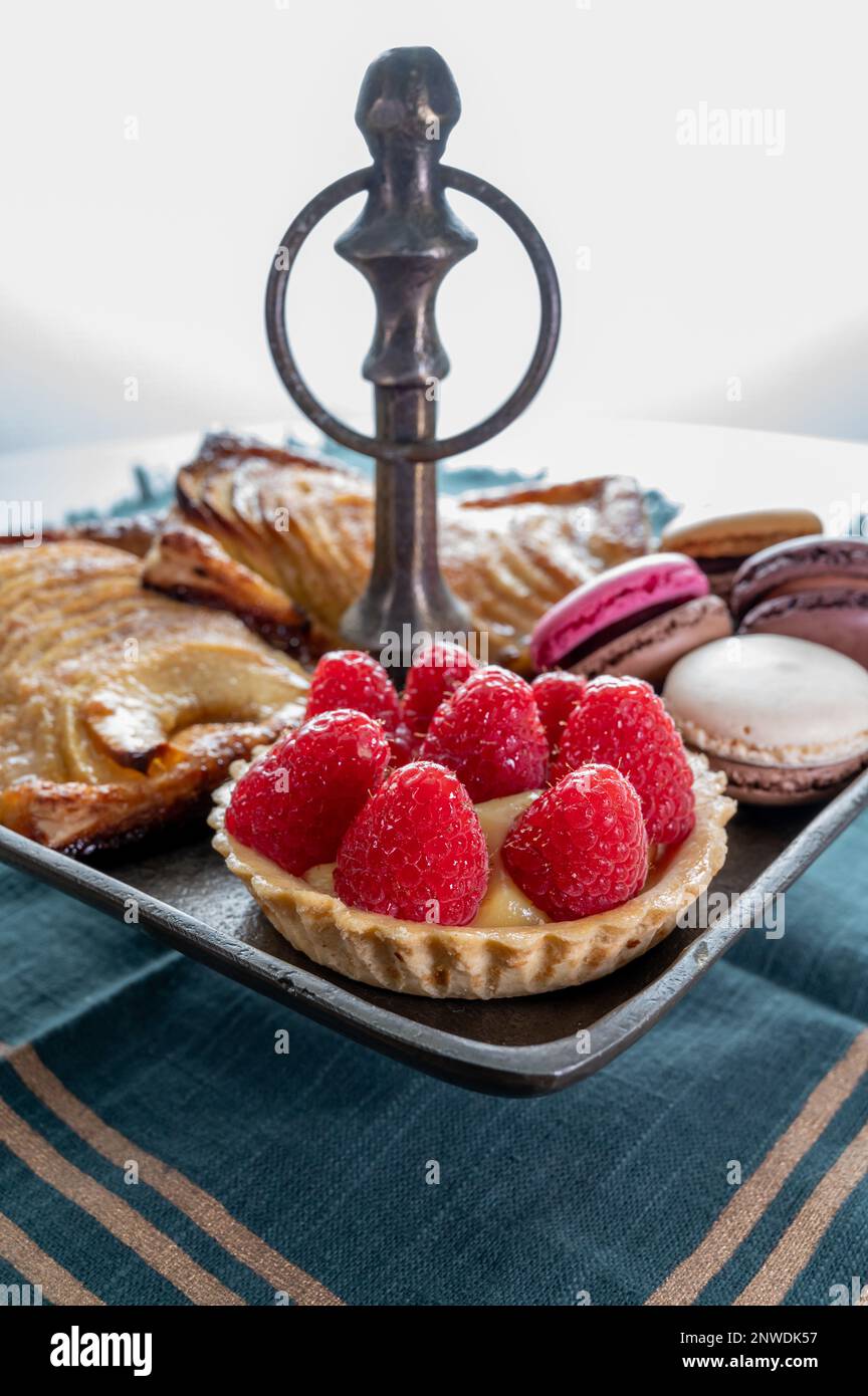 High tea with sweet baked tart with ripe red raspberry, apple cake with ...