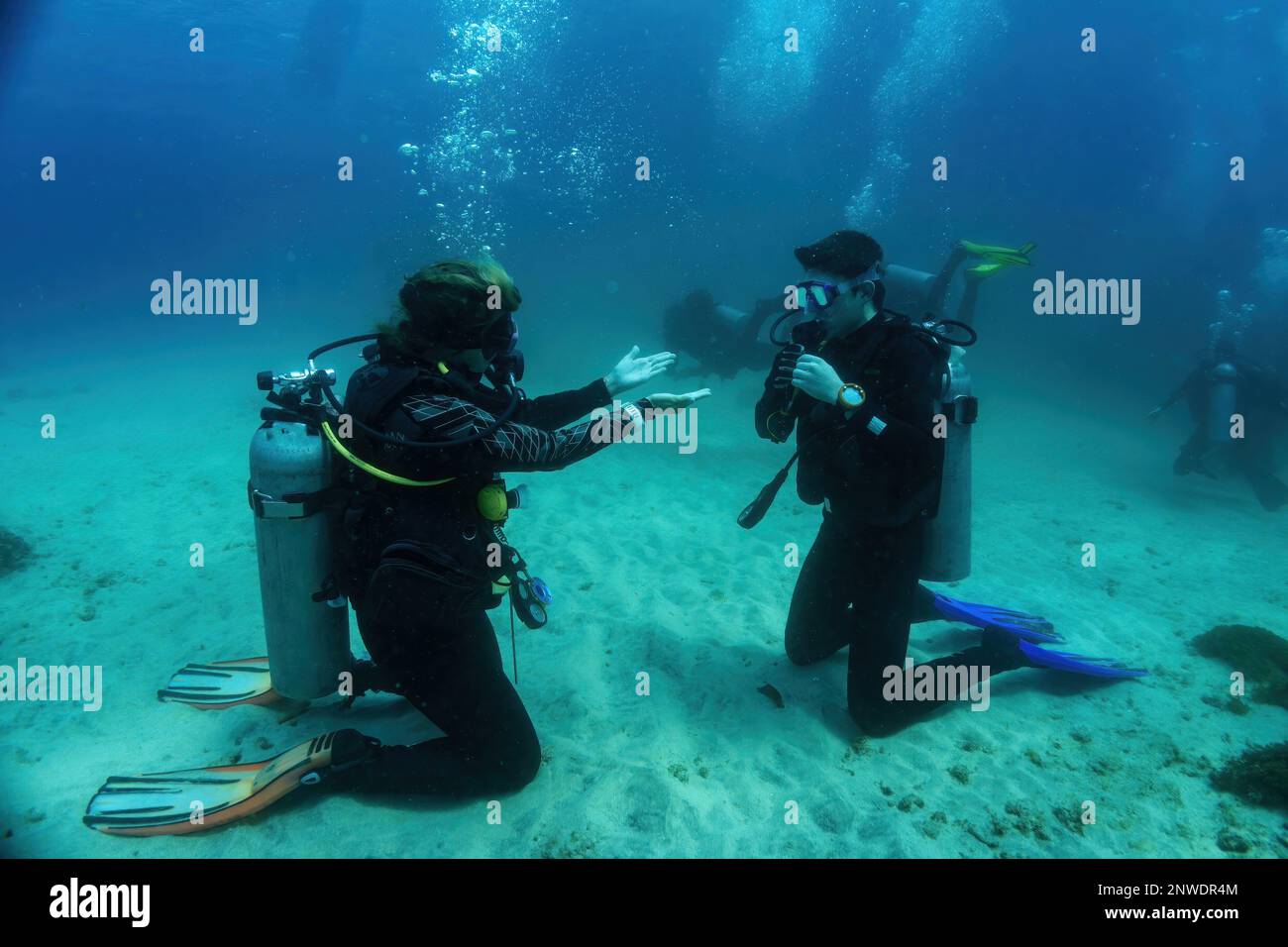 Underwater Scuba dive course training. Unidentified dive master explains with gestures what has to be done during the underwater dive lesson. Bali Stock Photo
