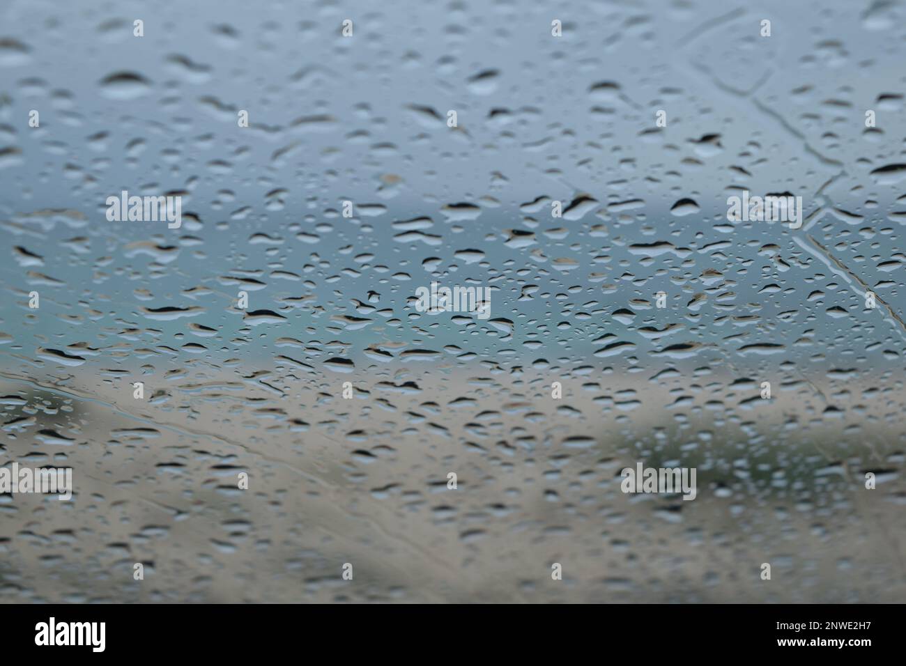 Gouttes de pluie sur le pare-brise d'une voiture, plage et mer en arrière-plan Stock Photo