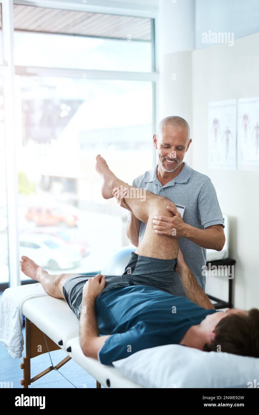 With careful exercises, your pain will soon be relieved. High angle shot of a handsome mature male physiotherapist treating a patient. Stock Photo