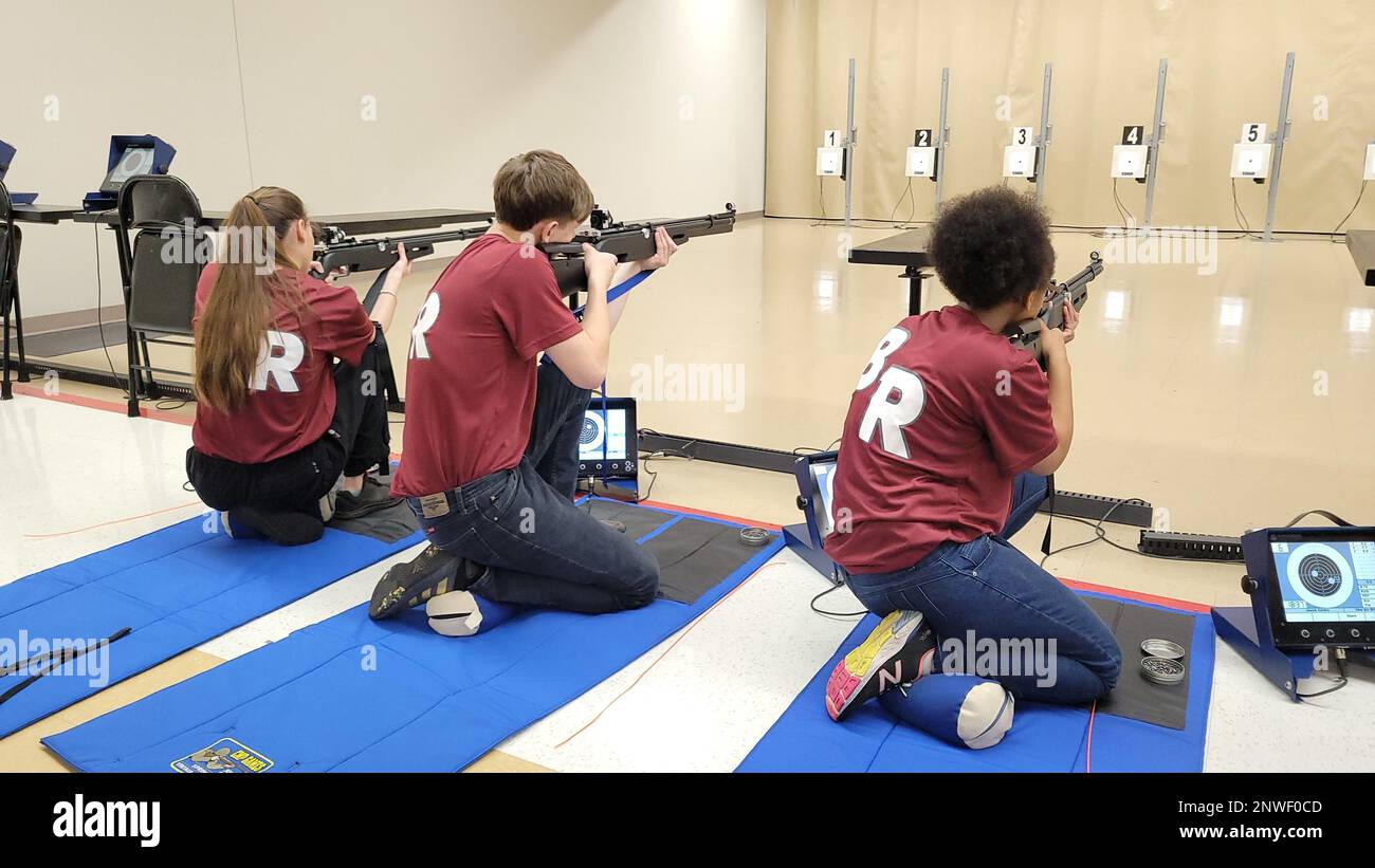 230113-N-LY580-1009 ANNISTON, Ala. (Jan. 13, 2023) Benjamin Russell High School Navy Junior Reserve Officers Training Corps Cadets Courtney Burgess, left, Brennen Luke, center, and Lylaishia Brown fire their air rifles from the kneeling position during the Area 8 2023 STS Match Championship at the Civilian Marksmanship Program Competition Center. Stock Photo