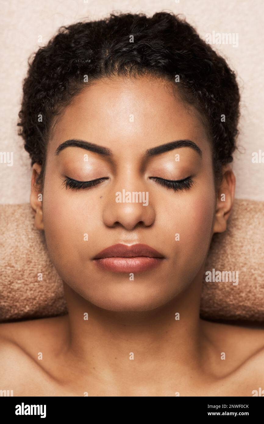 Young Black woman relaxing after getting face and body massage in spa