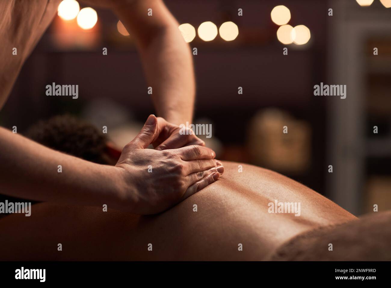 Massage therapist applying light touches when massaging back of client Stock Photo