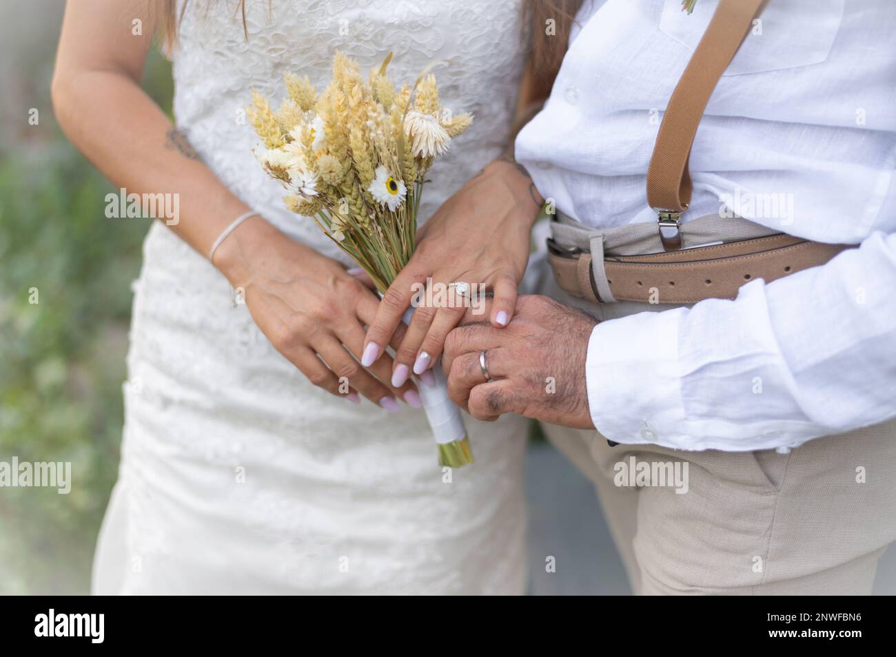 Mains de jeunes mariés, alliances et bouquet de fleurs Stock Photo