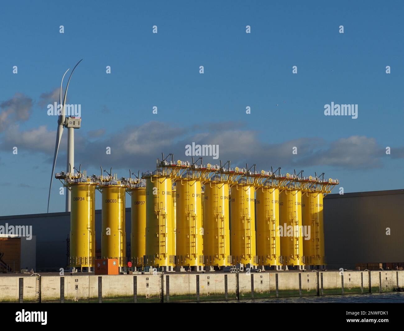The SIF company in the port of Rotterdam makes parts for windfarms to be used at sea. Their products are enormous, and very tough. These yellow bits g Stock Photo