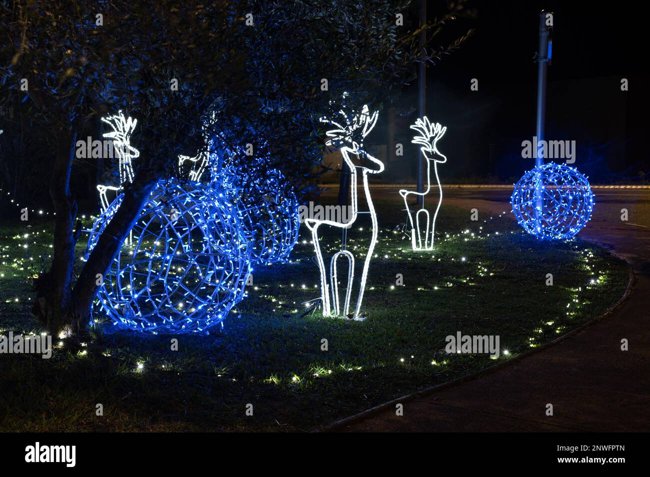 Décorations lumineuses de Noël, rennes blancs et boules bleues sur un tapis d'herbe Stock Photo