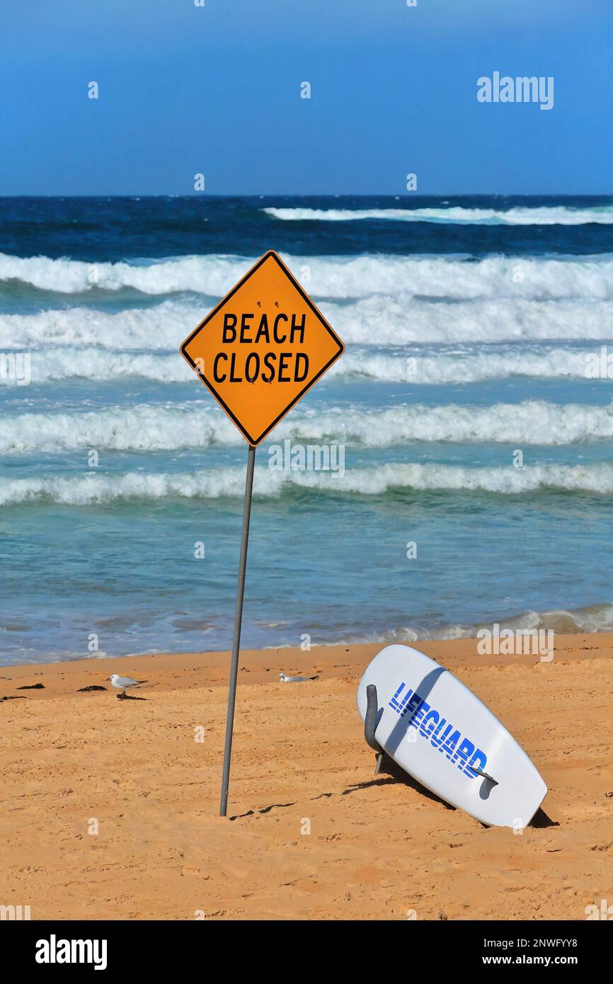 502 Manly Beach closed due to bad sea conditions-yellow signpost and white lifguard board. Sydney-Australia. Stock Photo