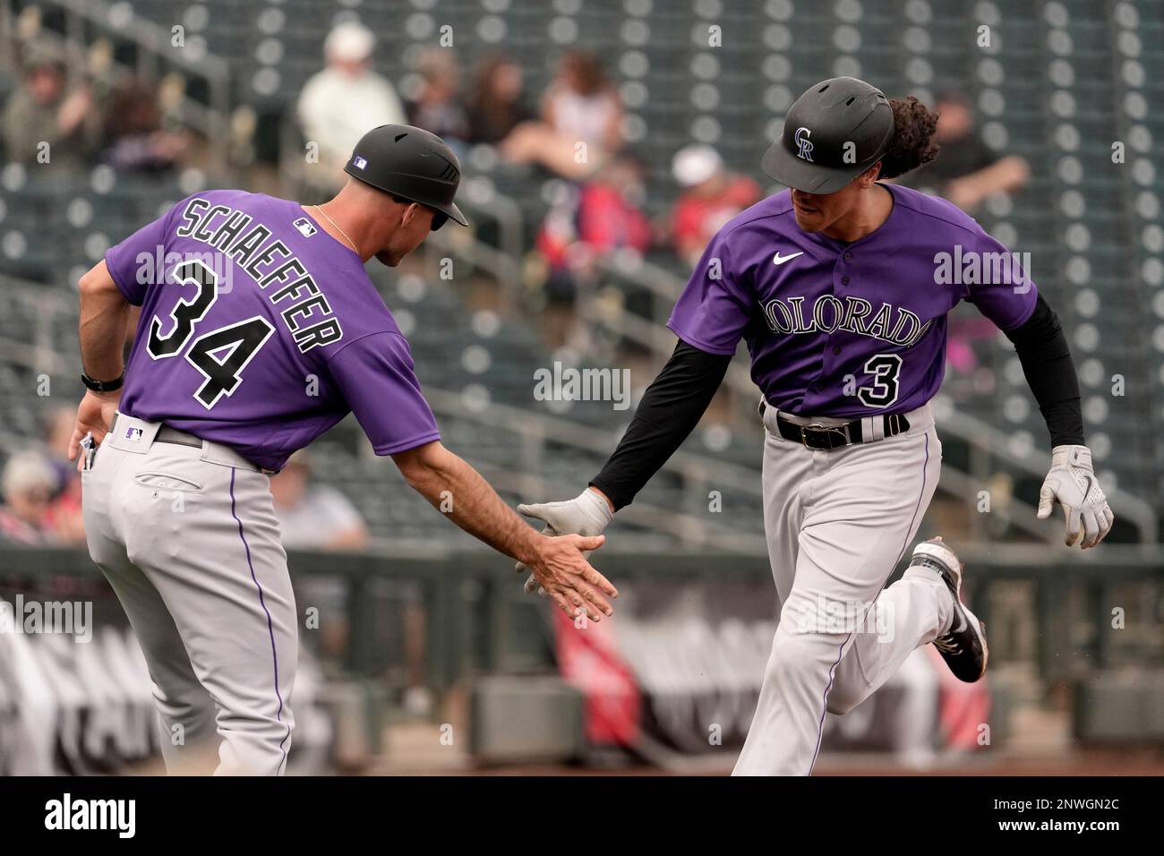 Colorado Rockies' Cole Tucker (3) celebrates with third base coach/infield  coach Warren Schaeffer (34) after hitting a solo home run during the third  inning of a spring training baseball game against the