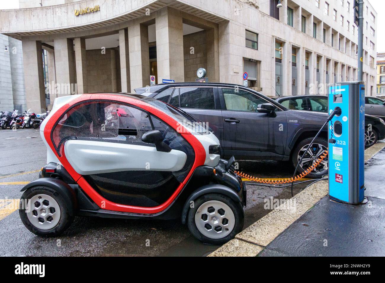 Milan, Italy, 27 February 2023.  A Renault Twizy electric microcar gets charged in a rainy day at an a2a charging station in a downtown Milan street. Stock Photo