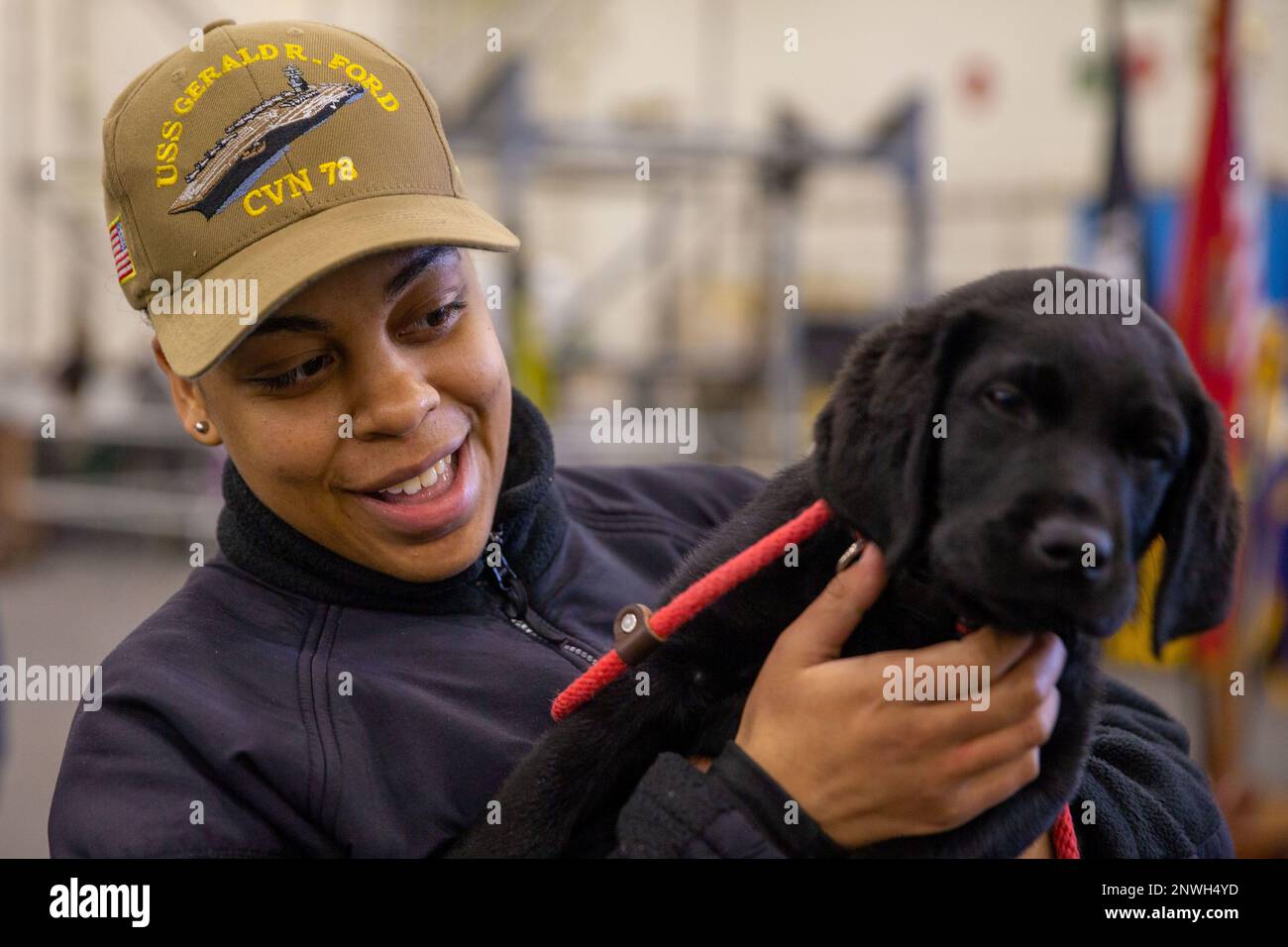 Seaman Tahaja Wilson, from Norfolk, Virginia, holds a dog, assigned to Mutts with a Mission, aboard the first-in-class aircraft carrier USS Gerald R. Ford (CVN 78), Feb. 1, 2023. Mutts with a Mission brought their puppies-in-training on board Ford as a morale-reinforcing opportunity by collaborating with the ship’s Morale, Welfare and Recreation department. Stock Photo