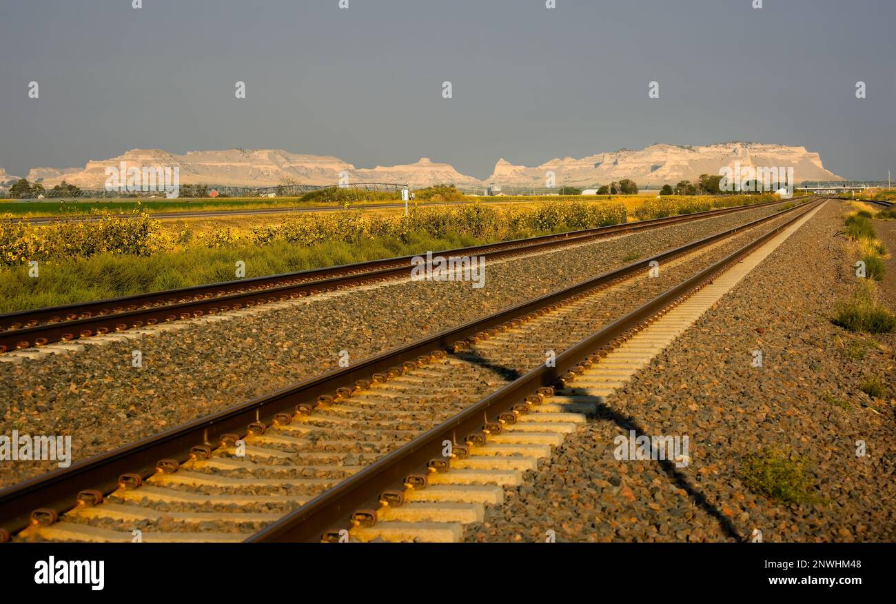 Railroad heading across the Nebraska plain toward Scotts Bluff National Monument in early morning light Stock Photo