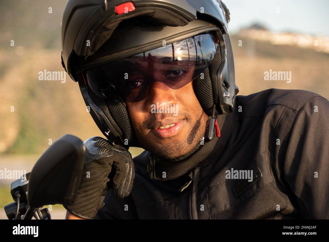 Close up of an African American biker wearing safety gear. He smiles at