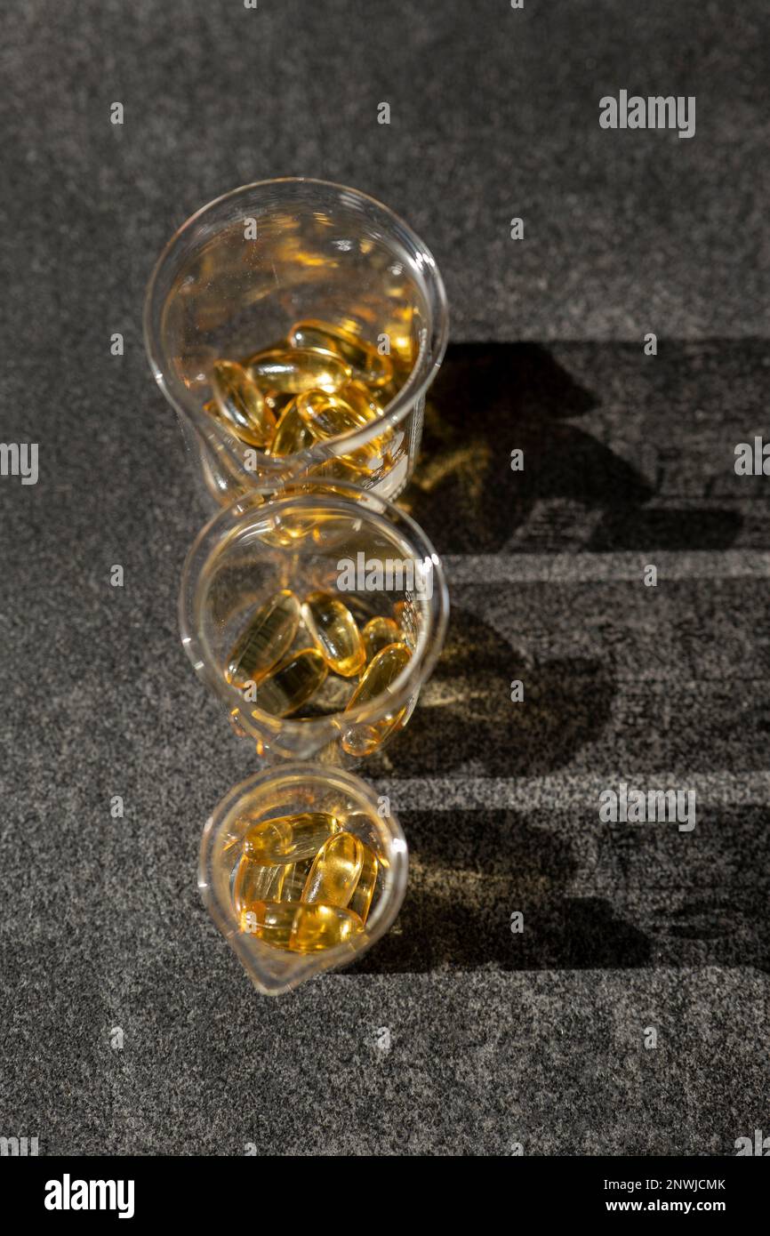 Fish oil capsules in laboratory flasks on a slate background in hard ...