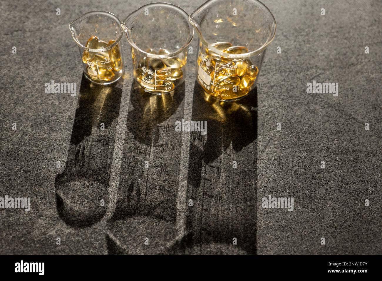 Cod Liver Oil.Fish oil capsules in laboratory flasks on a black slate ...