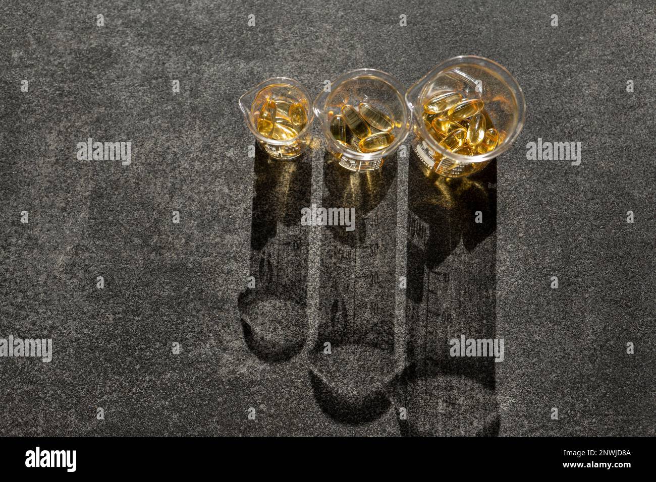 Cod Liver Oil.Fish oil capsules in flasks on a black slate background ...