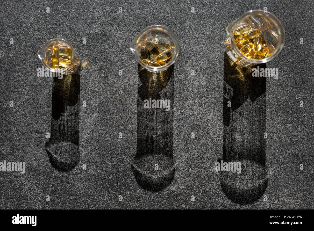 Fish oil capsules in laboratory flasks on a black slate background in ...