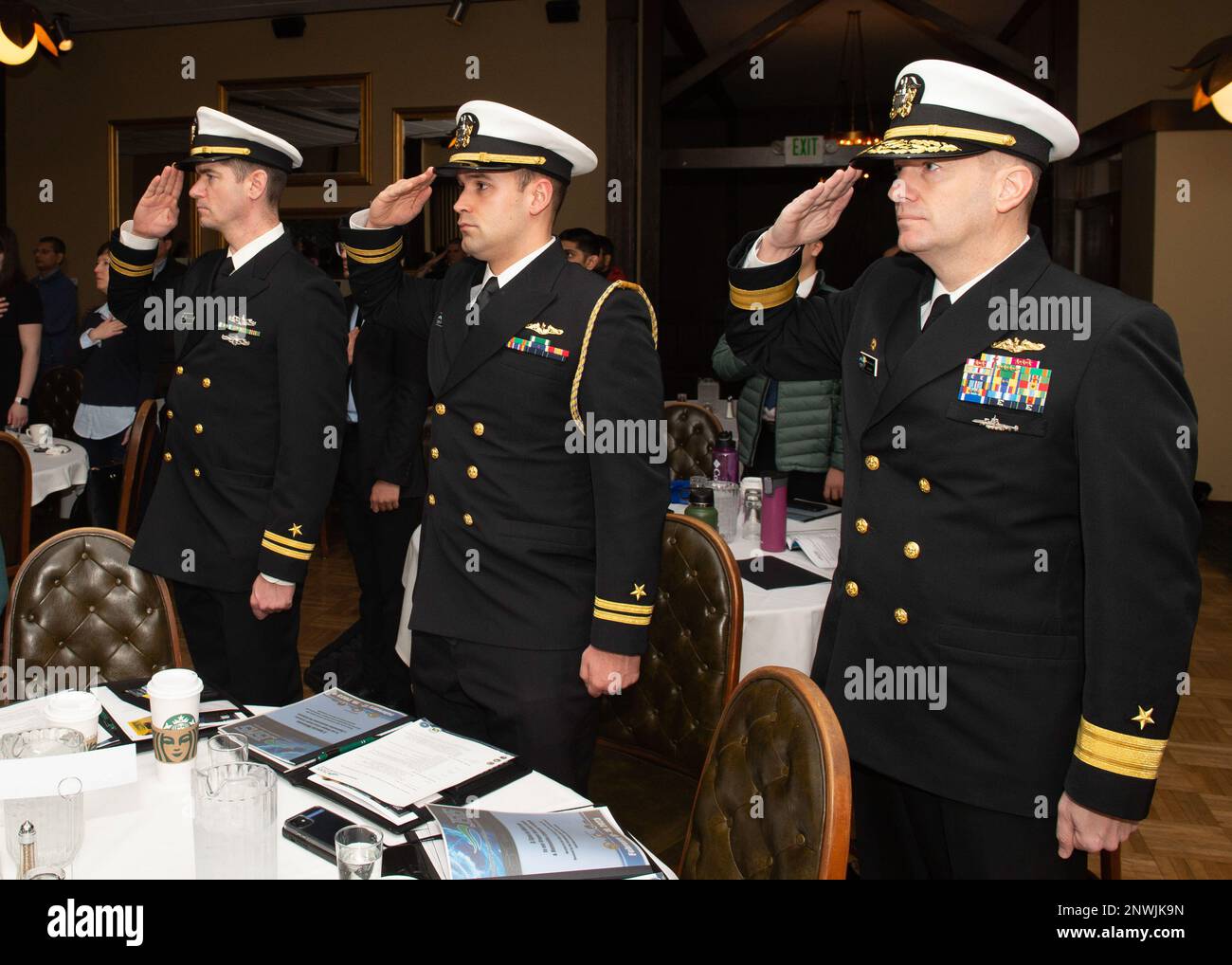 230218-N-ED185-1010  BREMERTON, Wash. (Feb. 18, 2023) Rear Adm. Mark Behning, commander, Submarine Group 9, right, Lt. Christian White, the Submarine Group 9 flag aide, and Lt. Corey T. Jones, the Submarine Group 9 public affairs officer, salute during the parading of the colors during the Junior Science and Humanities Symposium (JSHS) in Bremerton, Washington, February 18, 2023. The JSHS is a Department of Defense sponsored science, technology, engineering and mathematics (STEM) program that encourages high school students to conduct original research in the fields of STEM. Stock Photo