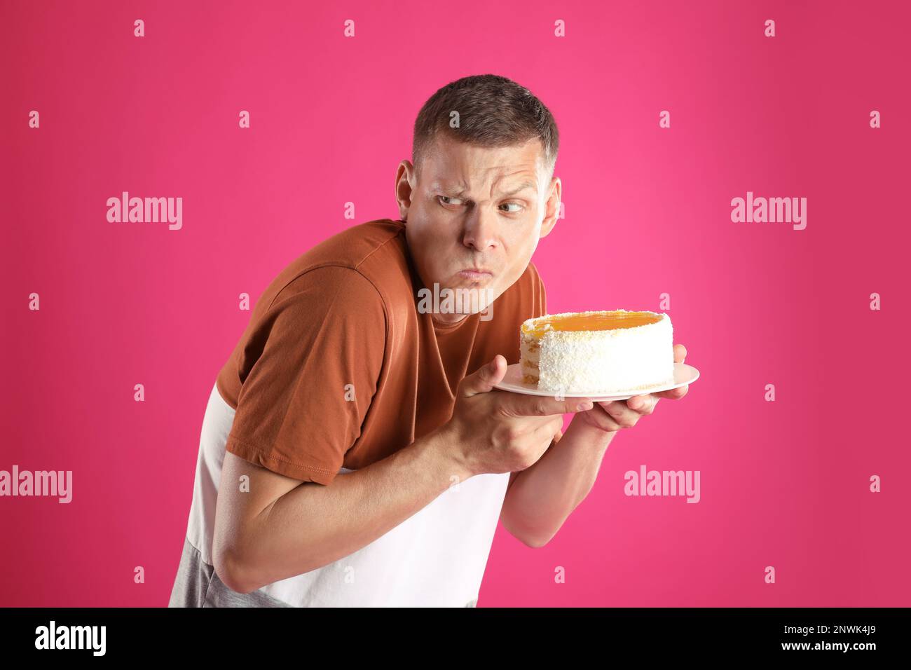 Greedy man eating tasty cake on pink background Stock Photo Alamy