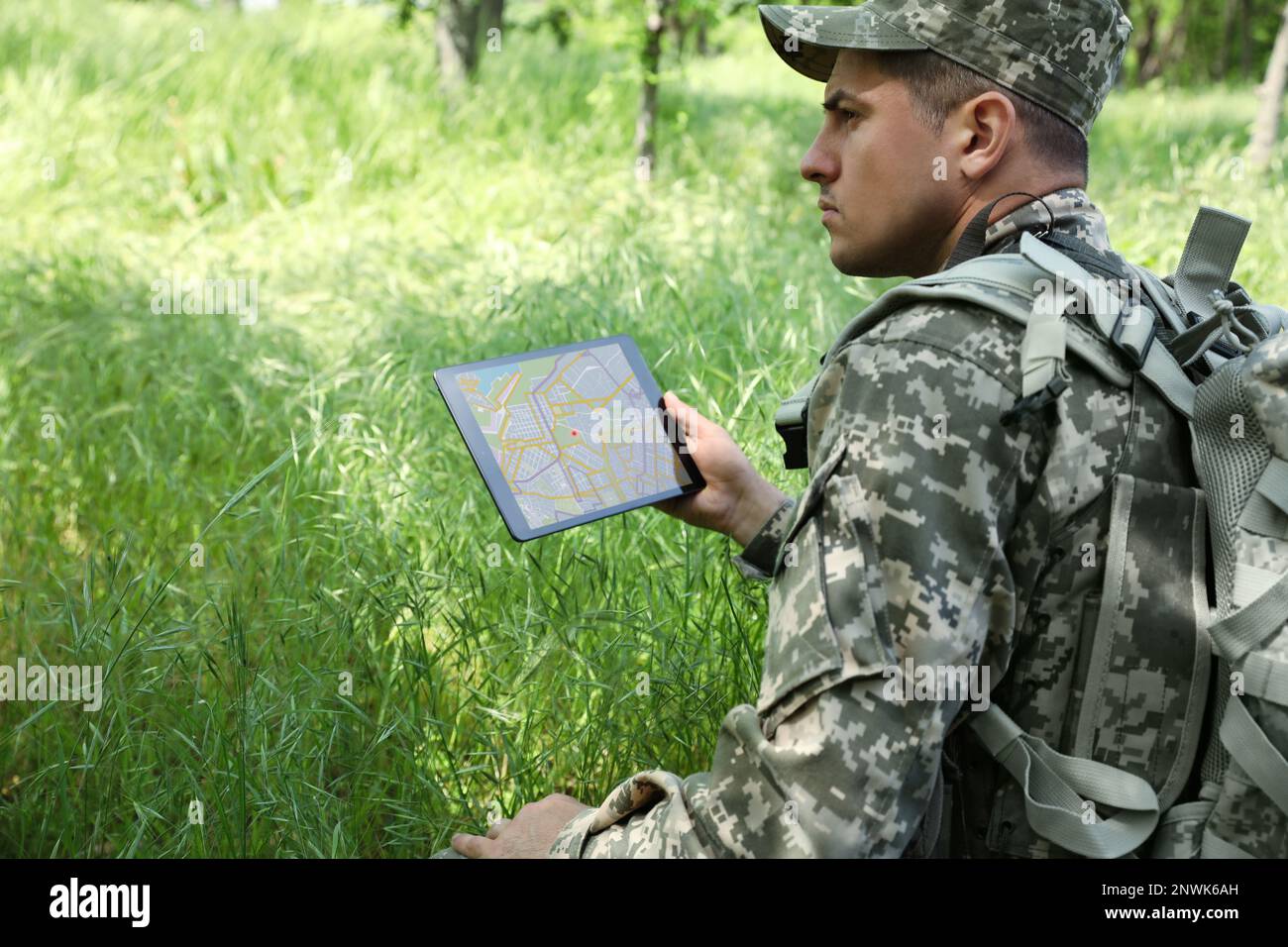 Soldier with backpack using tablet in forest Stock Photo