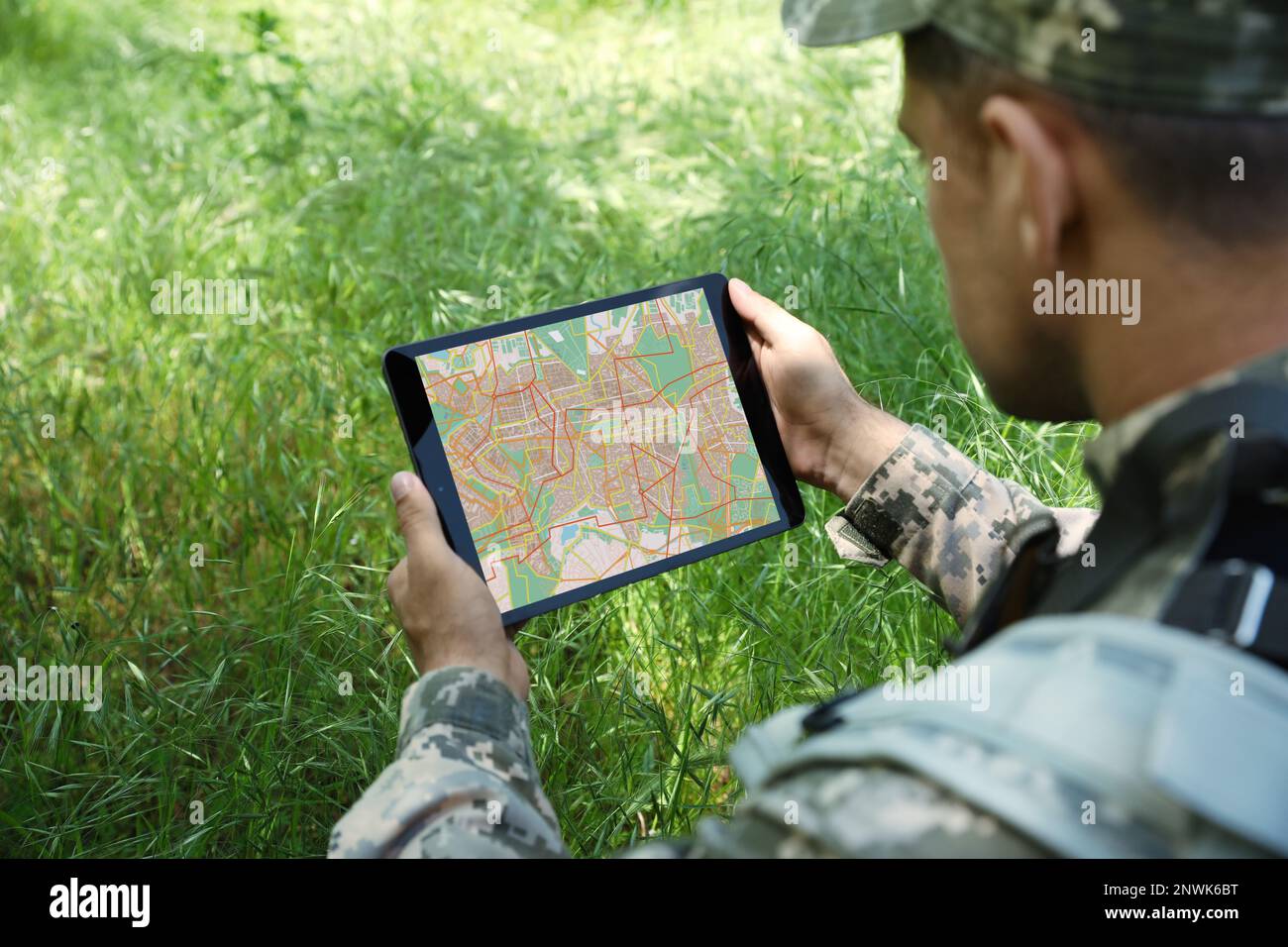 Soldier using tablet in forest, closeup view Stock Photo
