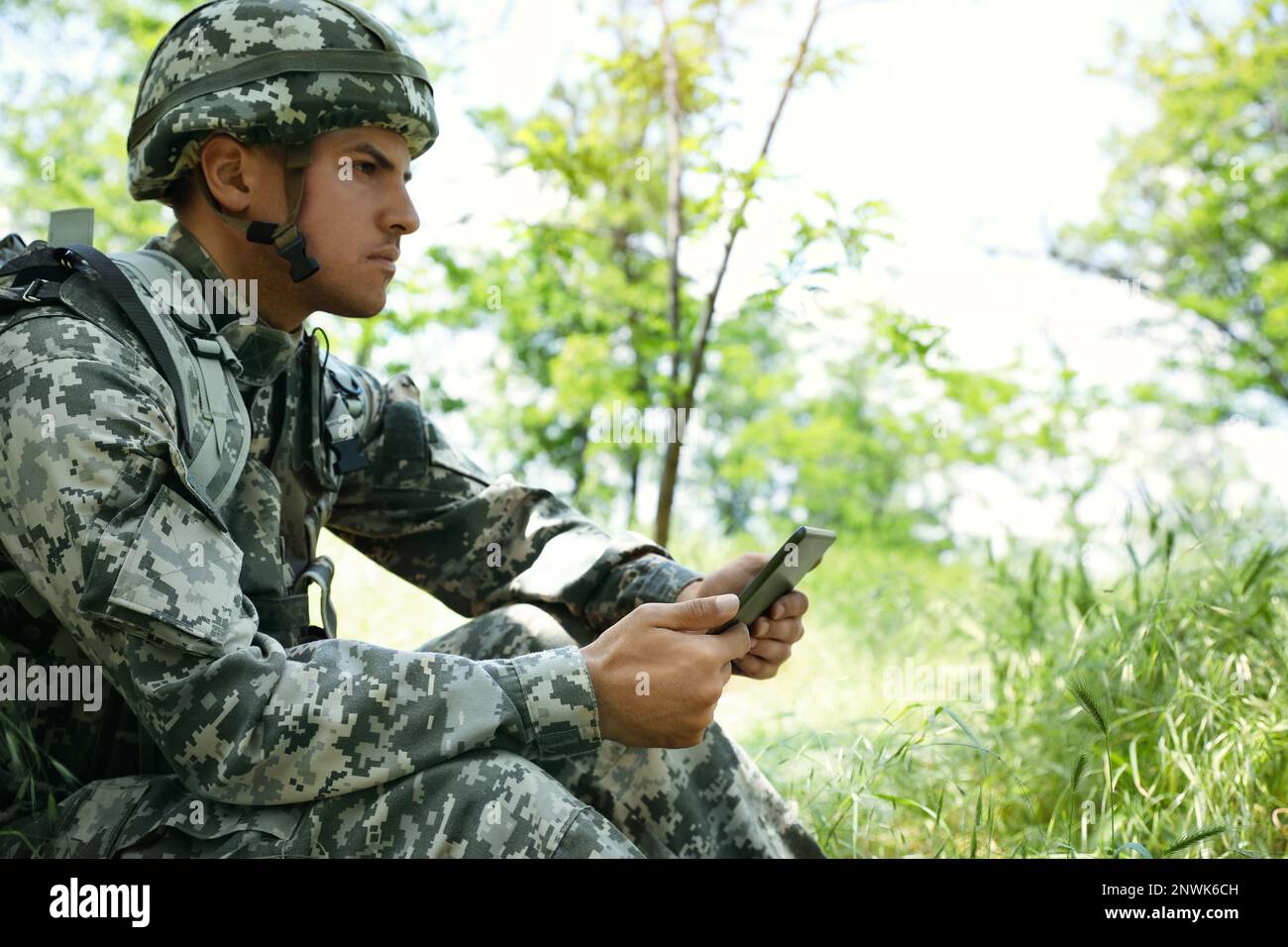 Soldier with backpack using tablet in forest Stock Photo
