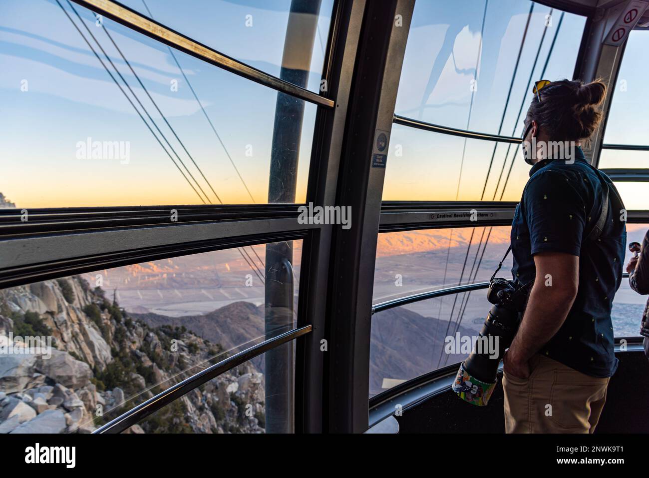 Man, tourist riding the Palm Spring aerial tramway to San Jacinto Peak Park in California during fall at sunset. Stock Photo