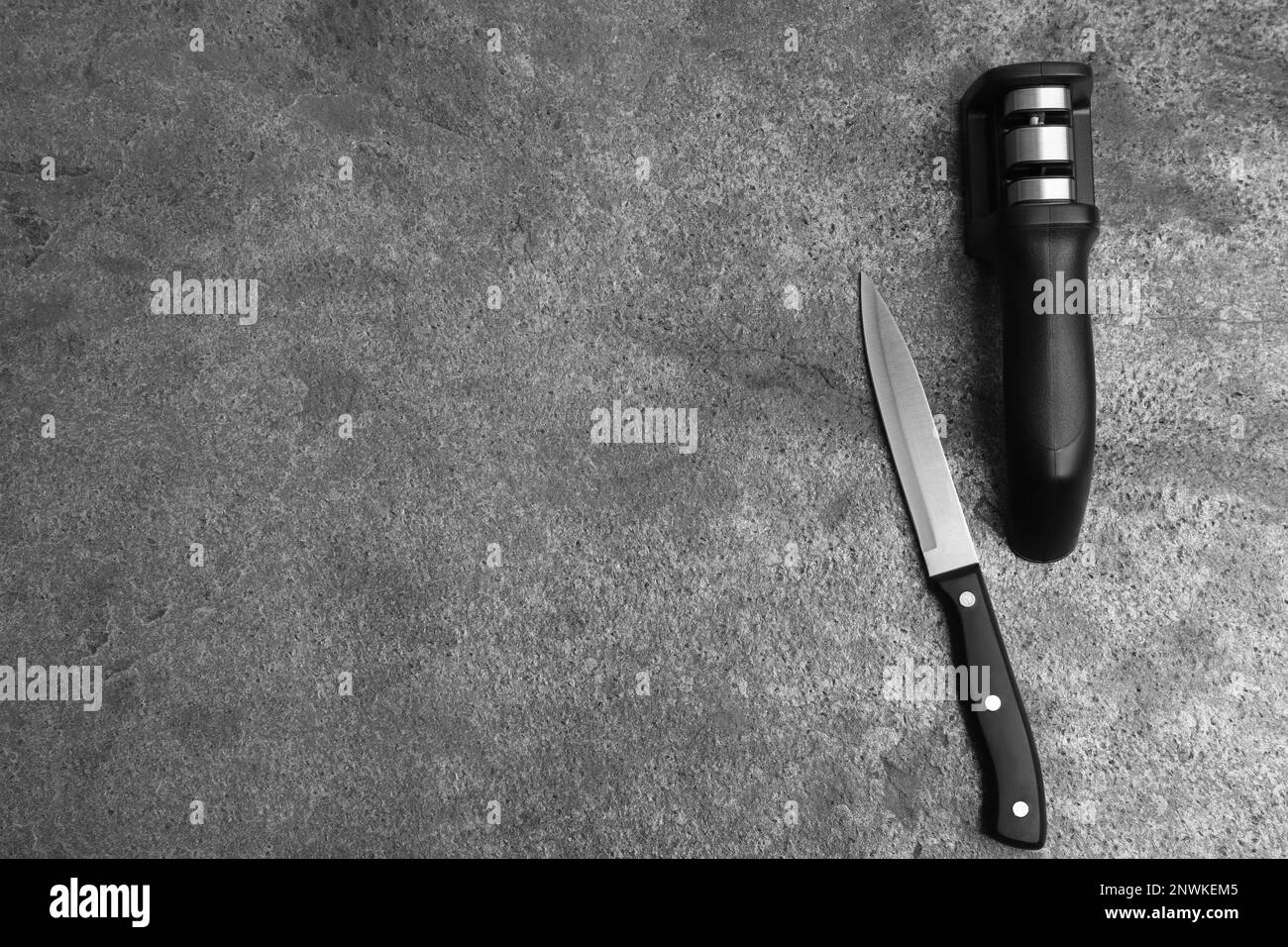 Modern handheld sharpener and knife on grey table, flat lay. Space for text Stock Photo