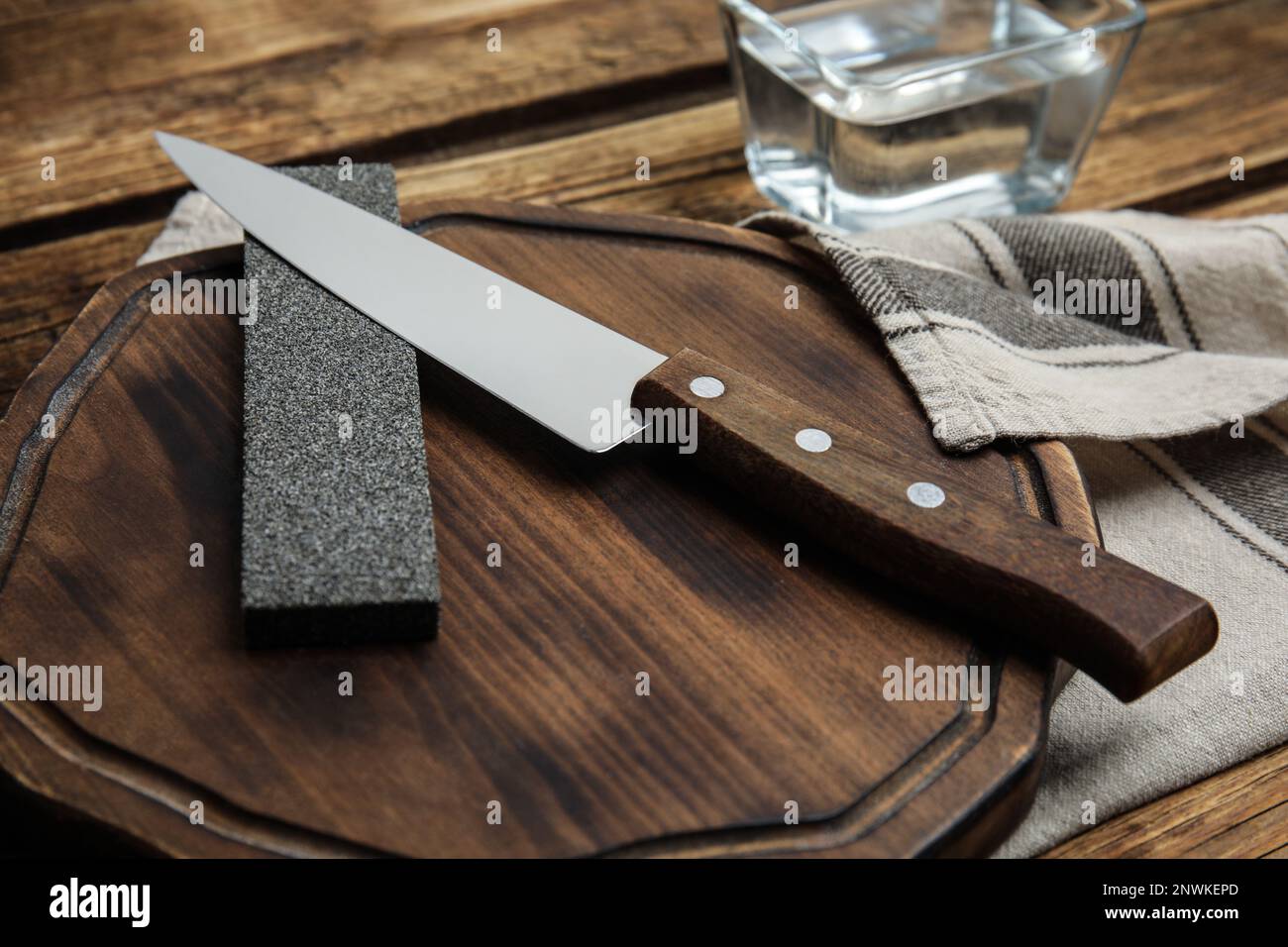 Man sharpening his pocket knife with a whetstone on a rustic wooden table  Stock Photo - Alamy