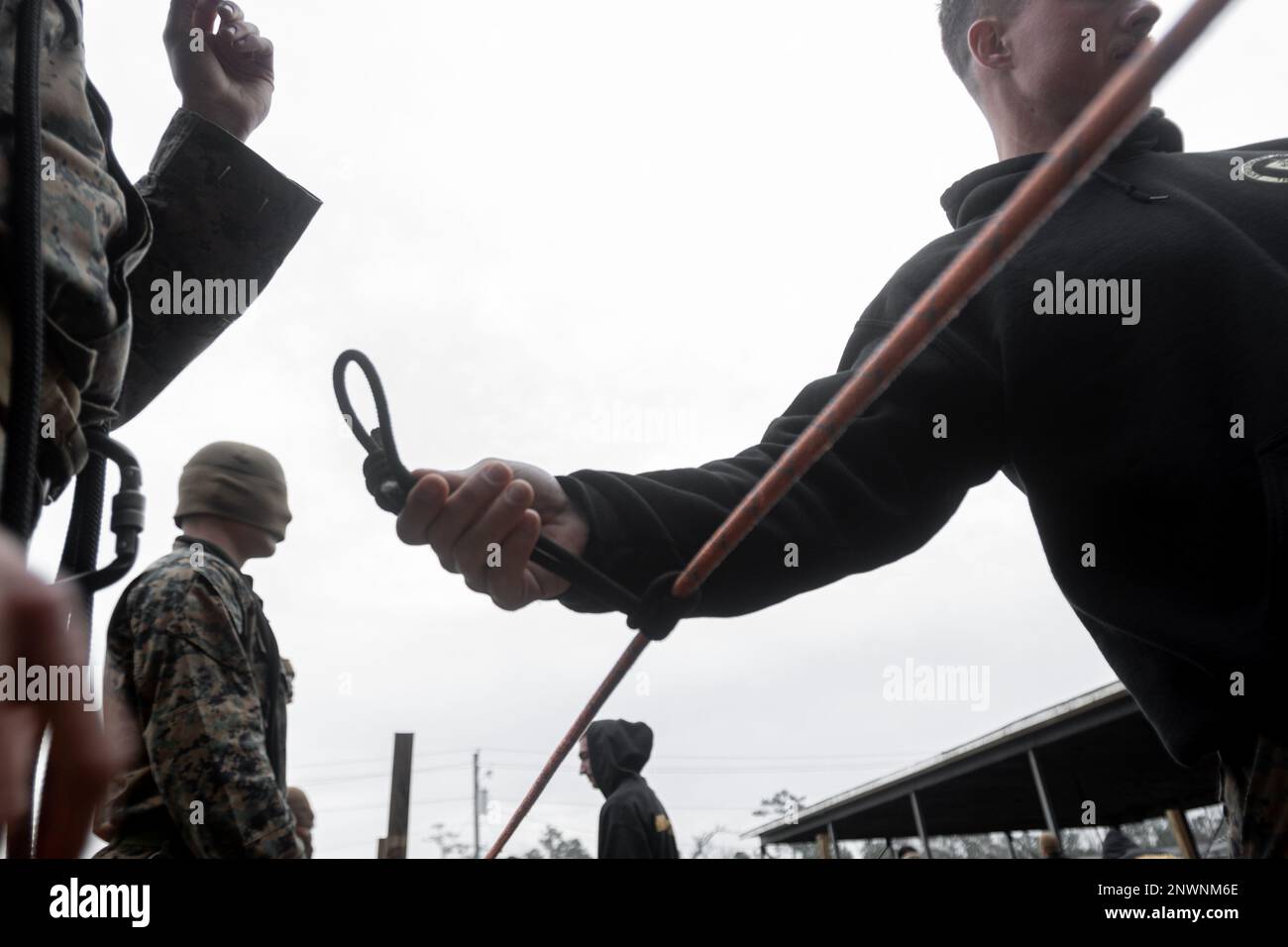 U.S. Marine Corps Sgt. Justin Adler, a native of Cincinnati, and a ropes and recovery instructor assigned to II Marine Expeditionary Force, Expeditionary Operations Training Group (EOTG), returns a knot after examining it for a blindfolded knot tying evaluation during the Assault Climber Course aboard Stone Bay, Marine Corps Base Camp Lejeune, North Carolina, Jan. 19, 2023. Assault Climber Course is an opportunity for the EOTG to train and evaluate the 26th Marine Expeditionary Unit’s ability to complete special individual and collective tasks, and evaluates their ability to conduct assigned m Stock Photo