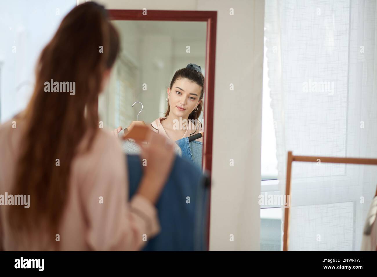 Girl standing in front of mirror and trying on clothes Stock Photo Alamy