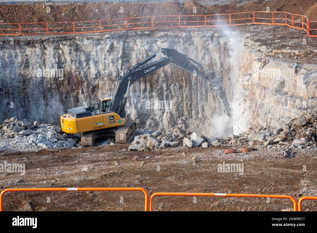 A contractor uses a hoe ram to clear out bedrock in preparation for
