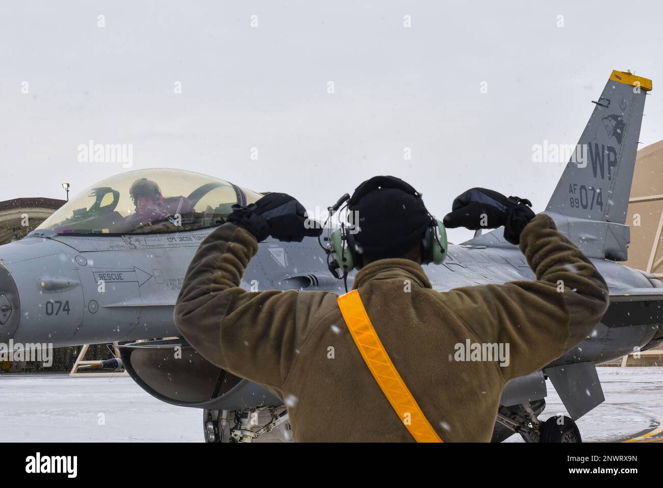 Airman 1st Class Zakkee Conwell, 80th Fighter Generation Squadron crew chief, poses with the ‘Crush ‘em’ hand gesture as U.S. Air Force Lt. Gen. Scott “Rolls” Pleus, 7th Air Force commander prepares to depart in an F-16 Fighting Falcon, at Kunsan Air Base, Republic of Korea, Jan. 26, 2023. The 80th Fighter Generation Squadron ‘Juvats’ are also known as the Headhunters. Stock Photo
