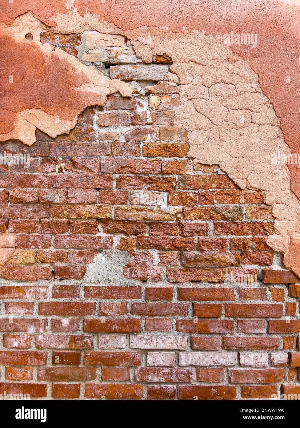 Faint red painting remnant on the brick wall of an old building. Wall background in design loft style. Grunge reddish brown colored with copy space. Stock Photo