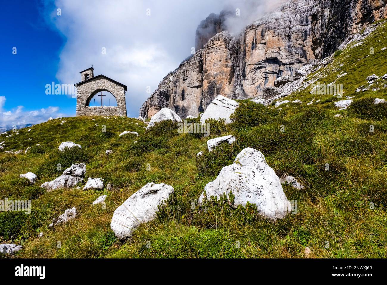 The small chapel near the mountain hut Rifugio Maria e Alberto al Brentei in Brenta Dolomites, surrounding rock cliffs in the distance. Stock Photo