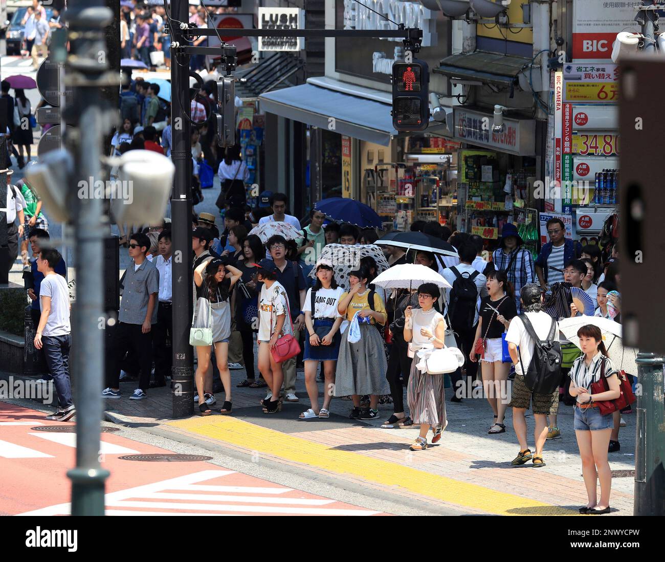 Pedestrians wait in the shade for a traffic light to change in 