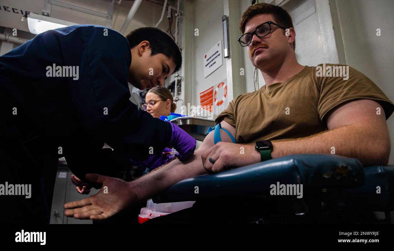 230123-N-XK047-1074    Hospital Corpsman 2nd Class Barbara Alvarez, left, draws blood from Aviation Support Equipment Technician Airman Garrett Depp during a medical readiness event aboard amphibious assault ship USS Makin Island (LHD 8), Jan. 23, 2023 in the South China Sea. Medical readiness includes updating medical records, administering immunizations, periodic health evaluations and HIV testing. The Makin Island Amphibious Ready Group, comprised of amphibious assault ship USS Makin Island (LHD 8) and amphibious transport dock USS Anchorage (LPD 23) and USS John P. Murtha (LPD 26), is oper Stock Photo