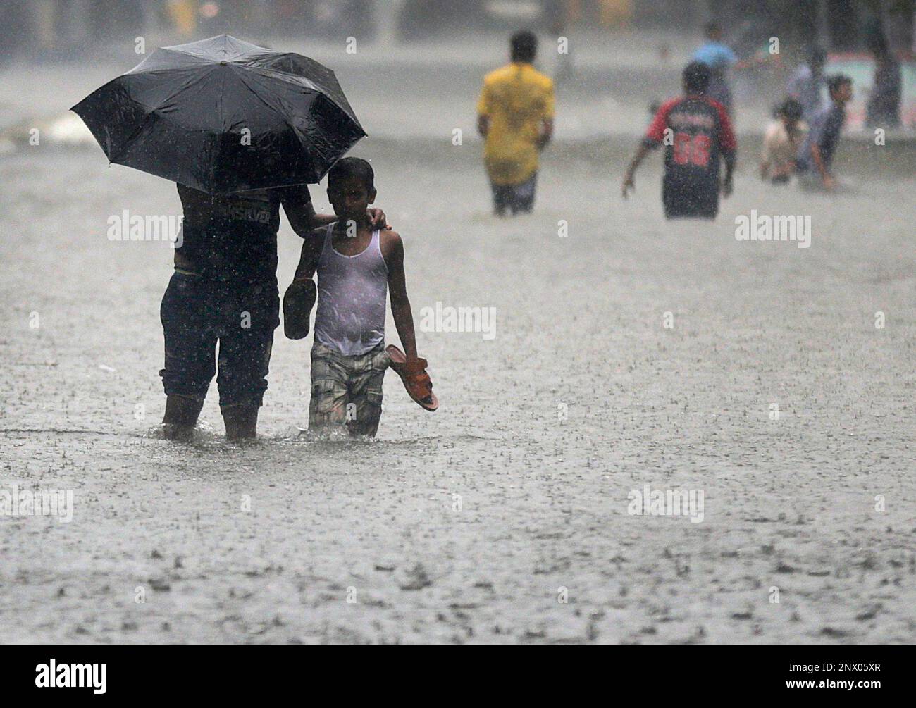 People walk through a waterlogged street during monsoon rains in Mumbai ...