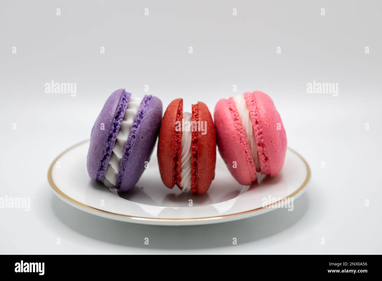 This image shows a close-up view of colorful French macaron confections with a cream filling, on a white background. Stock Photo