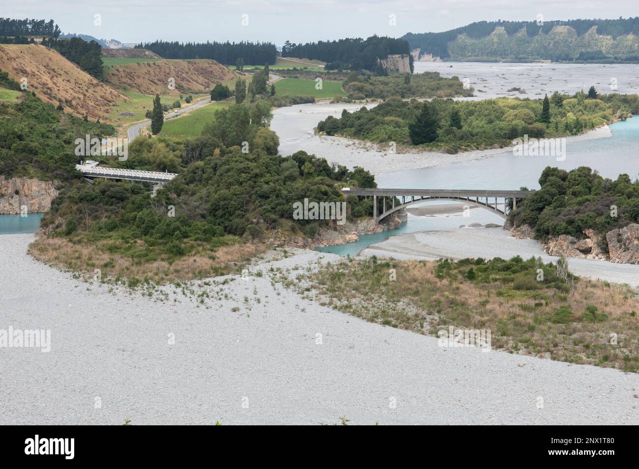 A wide landscape view of the Rakaia river at low water levels and a bridge over it in New Zealand. Stock Photo