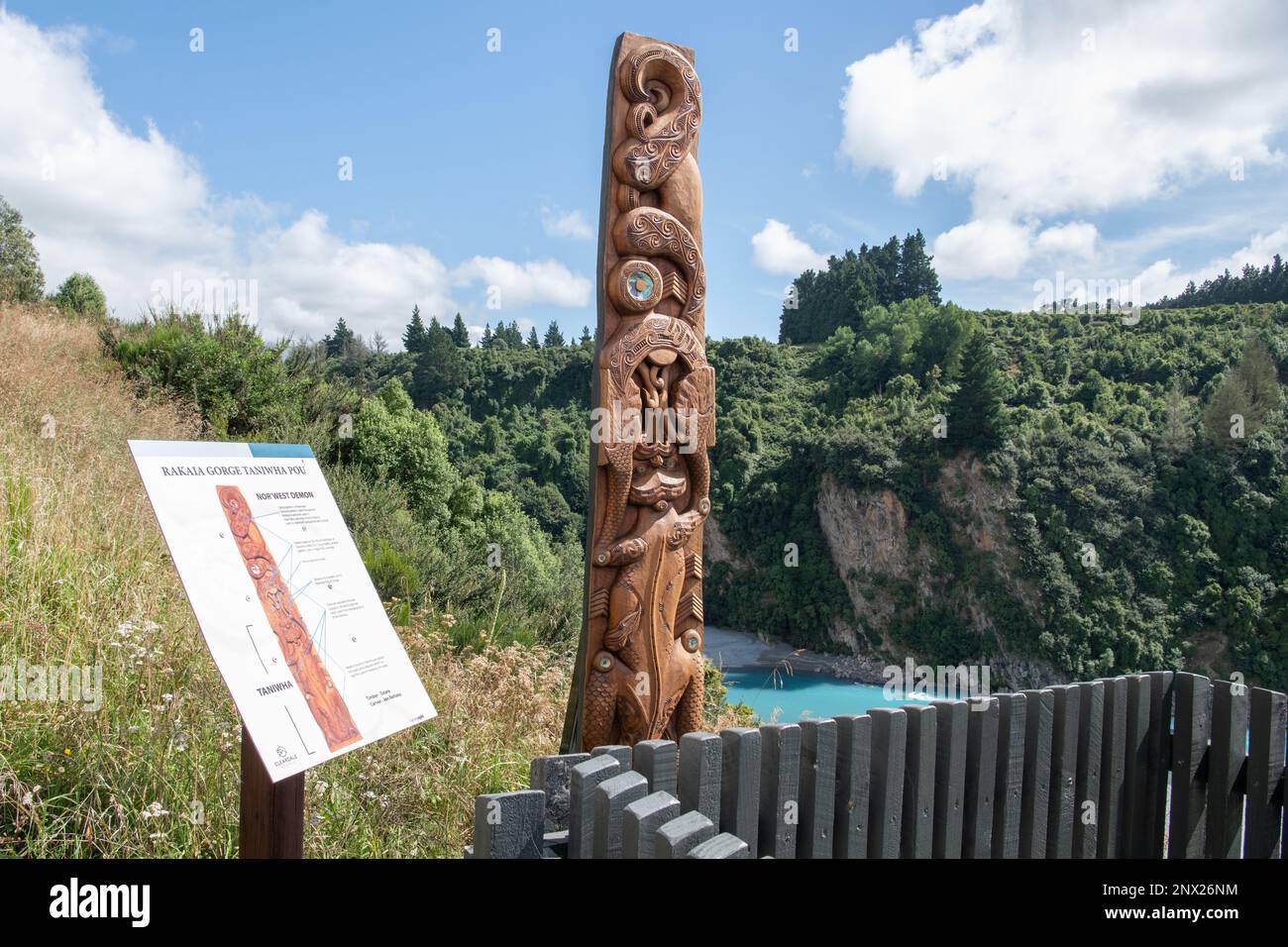 A wooden pou carving of a Taniwha from Maori mythology next to the Rakaia River and Gorge in Aotearoa New Zealand. Stock Photo