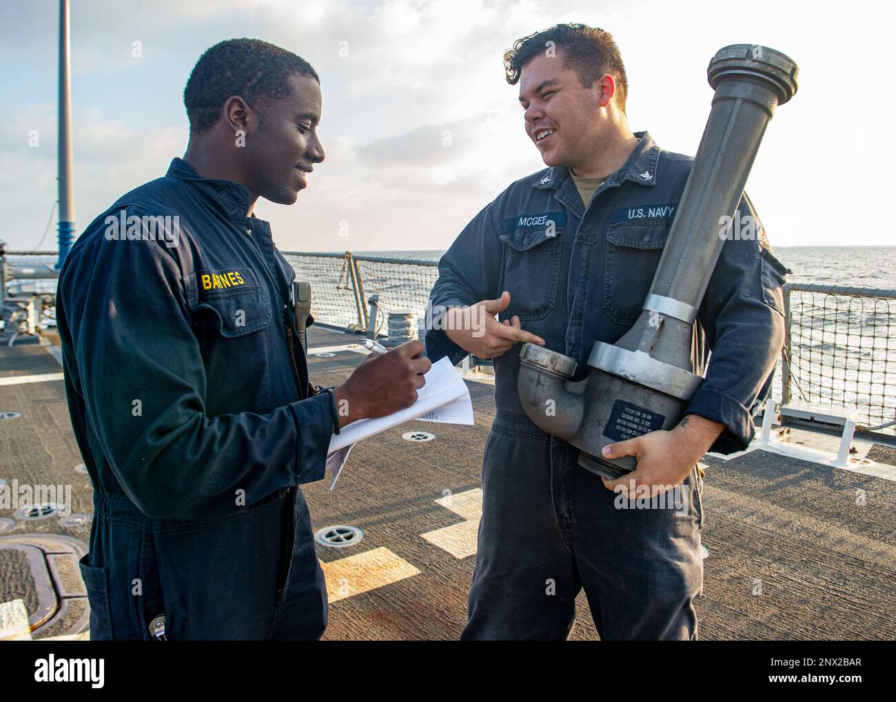 230215-N-NH267-1175 ARABIAN SEA (Feb. 15, 2023) Lt. j.g. Cedric Barnes,  left, discusses peri-jet dewatering capabilities with Hull Repair  Technician 3rd Class Andrew McGee during damage control training on the  flight deck of