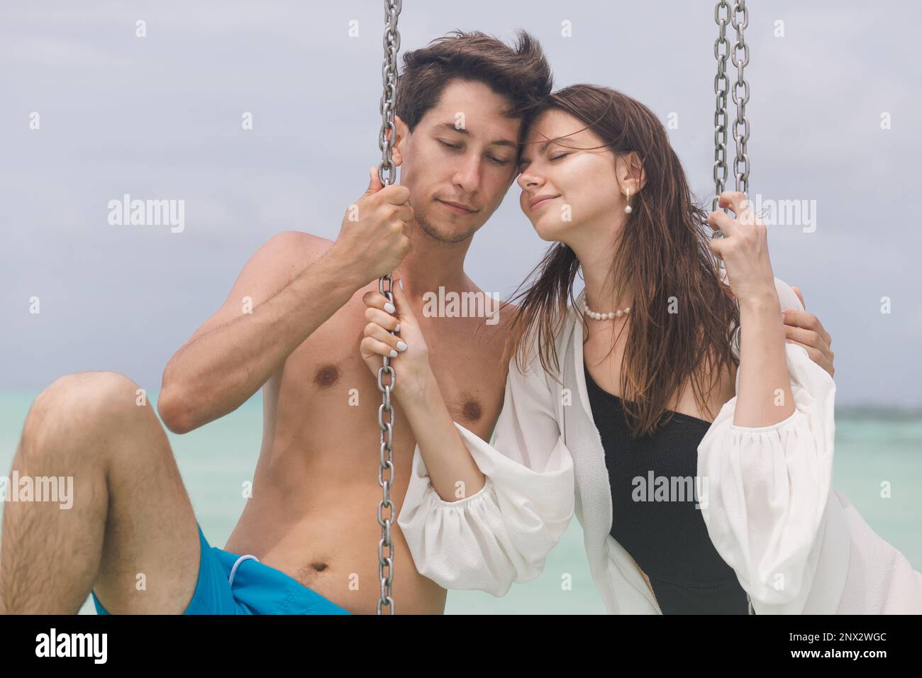 A young couple is swinging on a swing on a tropical beach in the Maldives Stock Photo image