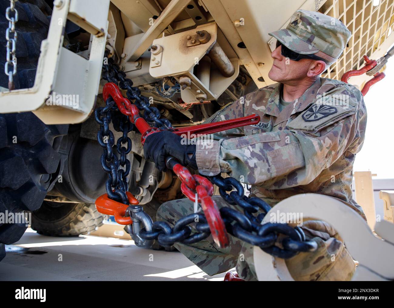 Arizona Army National Guard Sgt. Michael Stearns, a wheeled vehicle mechanic with the 3666th Support Maintenance Company, loosens the binders and chains used to hold an M977 A4 Heavy Expanded Mobility Tactical Truck (HEMTT) onto a trailer during a vehicle recovery mission, Feb. 5, 2023, at Papago Park Military Reservation (PPMR) in Phoenix. The inoperable HEMTT was transported from Pinal Air Park in Marana using a Modular Catastrophic Recovery System capable of transporting up to 35 tons. (Arizona Army National Guard photo by Sgt. 1st Class Brian A. Barbour) Stock Photo