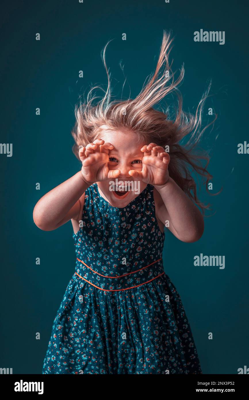 Blonde girl in flowery dress performs a scary and funny face Stock Photo