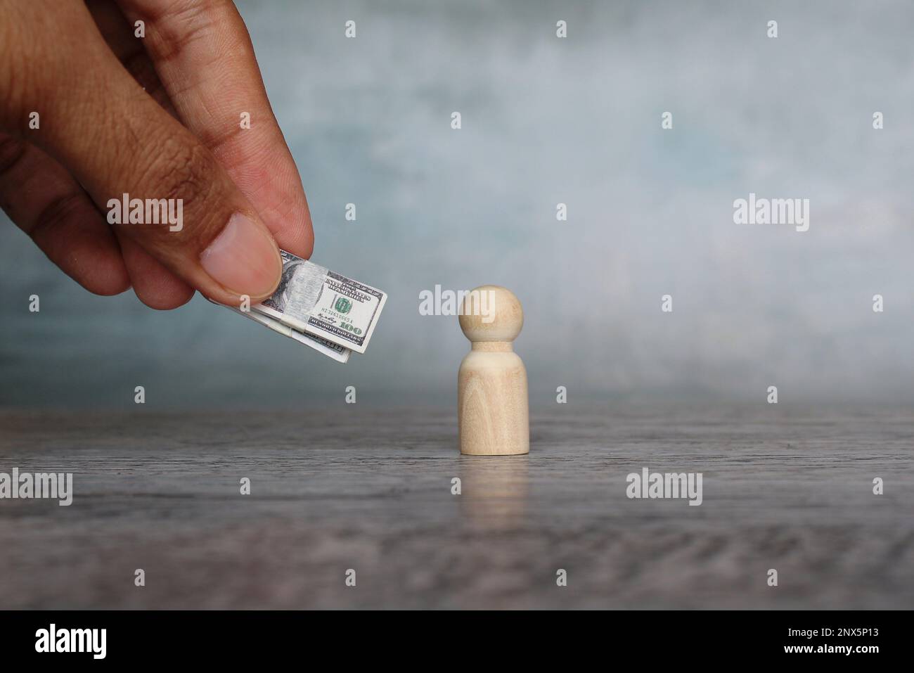 Hand giving money to wooden doll. Bonus, incentive, reward, compensation, investor, bribery concept Stock Photo